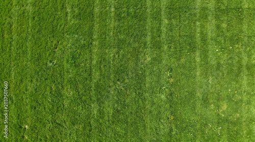 Aerial view of a vibrant green grassy field with distinct mowed stripes.