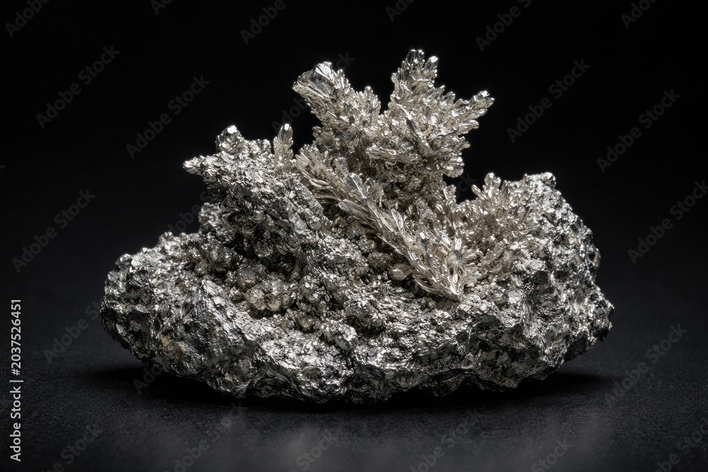 Fototapeta premium Silver mineral specimen presented on a smooth black backdrop surface