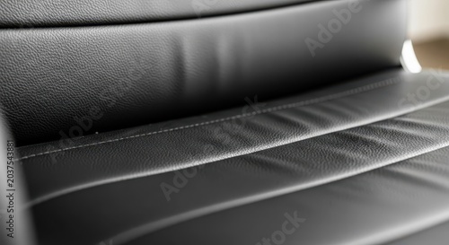 Close-up macro view of luxurious black leather office chair texture with detailed stitching and subtle lighting