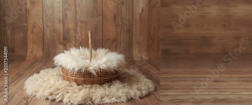 Baby photoshoot prop of wicker basket filled with white fur on natural wooden backdrop