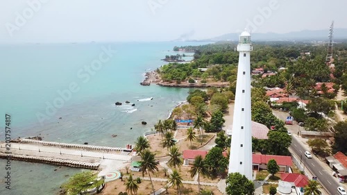 High Angle Aerial View of Historic White Lighthouse on Tropical Coastline with Turquoise Water