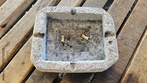 фотографія an ashtray that is very dirty with cigarette butts and ash inside, the ash has stuck to the ashtray, smoking is not good for your health