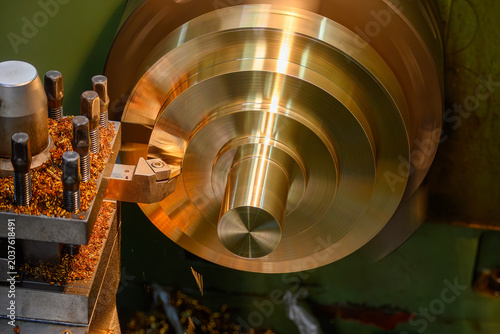 Obraz na plátně High-precision surface finish cut of a brass material part on a lathe turning machine in a blue-toned scene