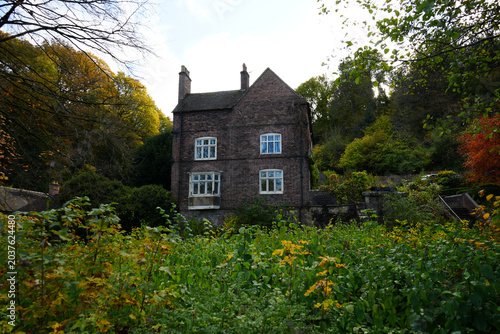 Traditional Brick House With White Windows Surrounded By Vibrant Autumn Foliage And Trees In Ironbridge, Shropshire, England, On A Bright Day.