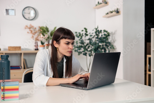 Foto Woman concentrating working on laptop in modern home office