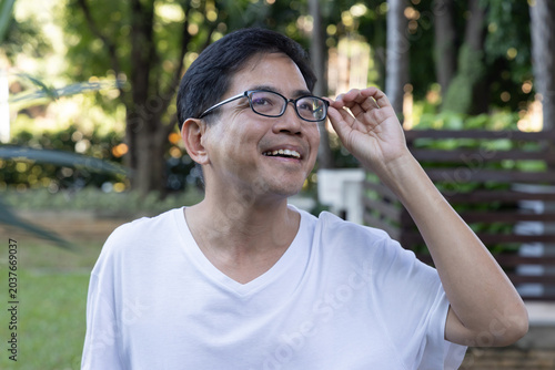 Foto Relaxed happy carefree middle age old Asian man taking evening walk, breathing t