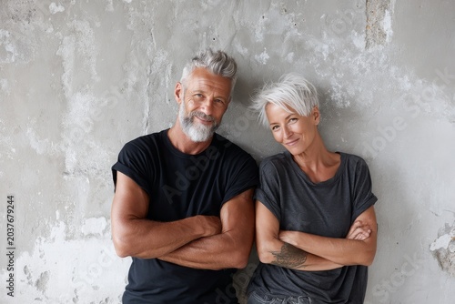 Portrait of a happy couple in their 60s dressed in a casual t-shirt on empty modern loft background