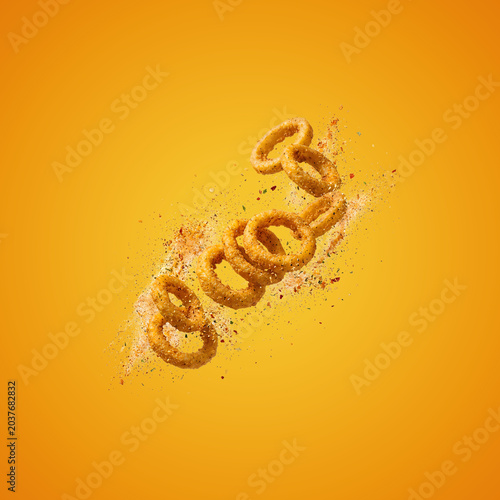 Onion rings falling on yellow background with spices