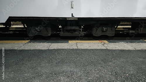 Foto Close up of train wheels and undercarriage at a station platform at night