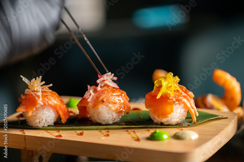 Foto A chef using tweezers to garnish gourmet salmon nigiri sushi served on a wooden board