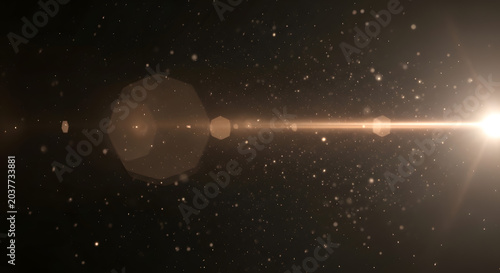Golden light flare with sparkling dust particles on a dark black background
