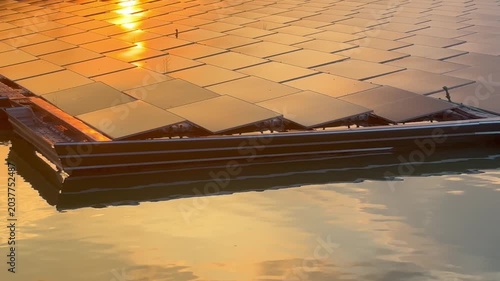 Floating solar panels and solar-powered water aerator on a lake during a golden sunset, renewable green energy footage