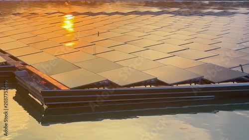 Floating solar panels and solar-powered water aerator on a lake during a golden sunset, renewable green energy footage