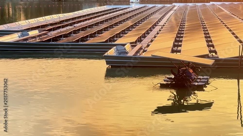 Floating solar panels and solar-powered water aerator on a lake during a golden sunset, renewable green energy footage