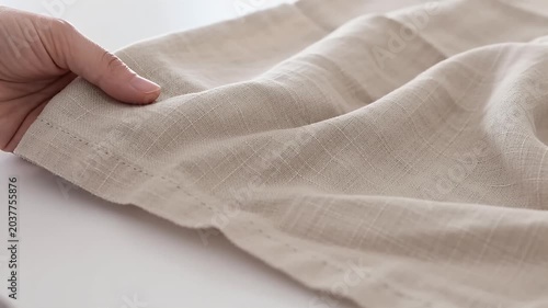 Person touching a piece of soft beige linen fabric