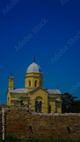 photo of a beautiful church with a yellow facade above which is a blue sky