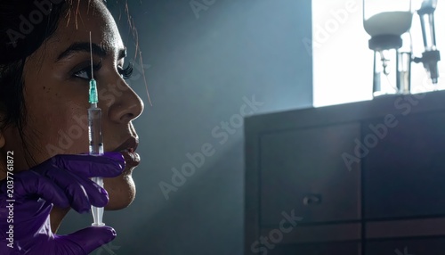 Nurse's hand in purple nitrile glove holding sterile syringe filled with clear liquid for medical procedure