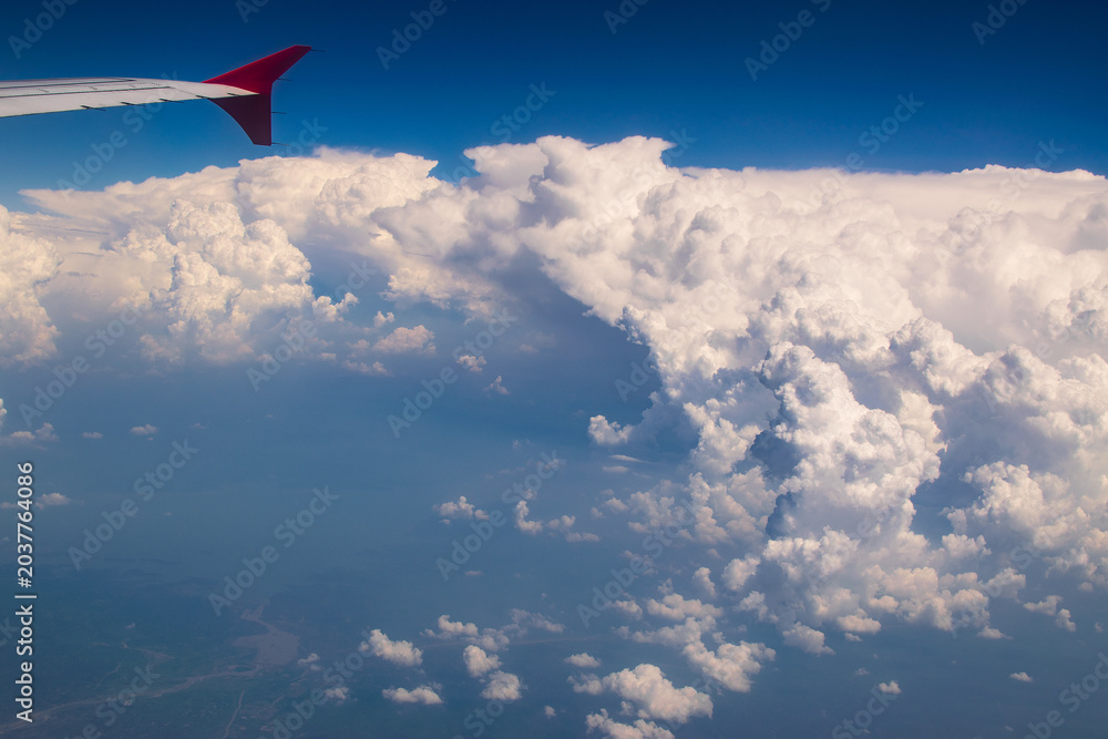 Fototapeta premium White clouds in sky with aeroplane wing. Image shot from flying aeroplane , cloudscape of India.