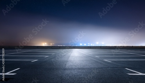 empty rooftop parking lot at night under a foggy sky