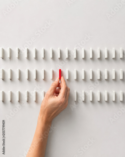 Hand picking one red chalk among many white ones. Concept of creativity, making a difference, and choosing a unique path.