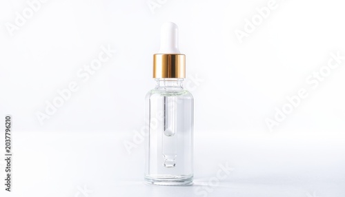 Clear glass dropper bottle with gold cap on white background