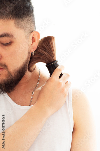 Man applying talcum powder with a barber's brush to his neck after a home haircut against a white background