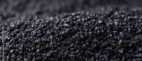 Close up texture of wet black sand with sparkling highlights and shallow depth of field