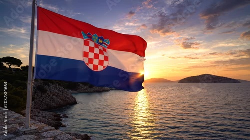 Croatian flag waving by the sea at sunset