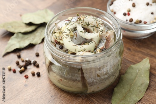 Fotografie Marinated herring with spices on wooden table, closeup