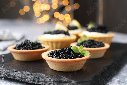Schilderij op canvas Tasty tartlets with black caviar on light grey table, closeup