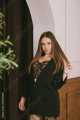 Fotografie A young woman in a black blazer and lace bodysuit stands near an arch posing pla