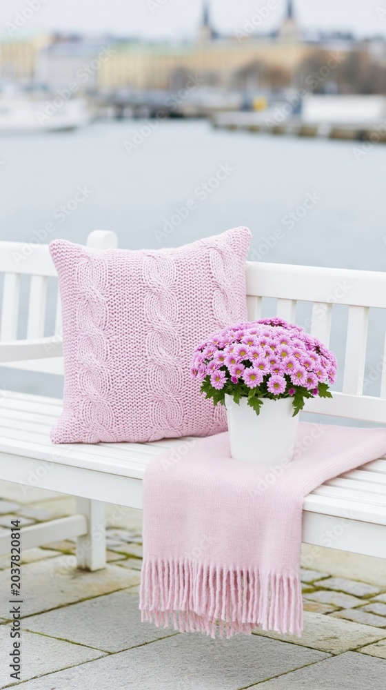 Obraz premium Pink cushion and flowers arranged on bench by waterfront