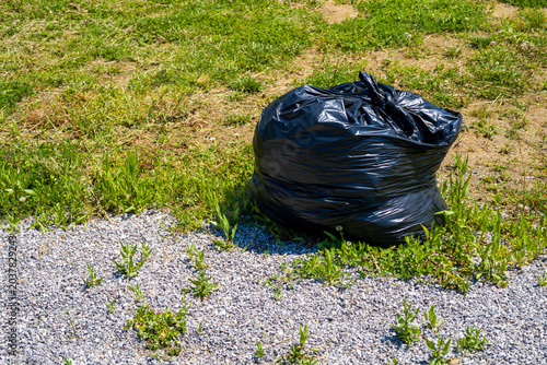 Black garbage bag on grass and gravel