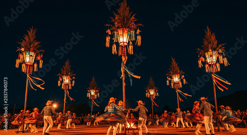 Traditional Balinese Penjor decorations illuminated at night during a festival.