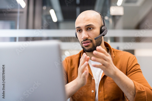 Call center agent communicating with headset and laptop