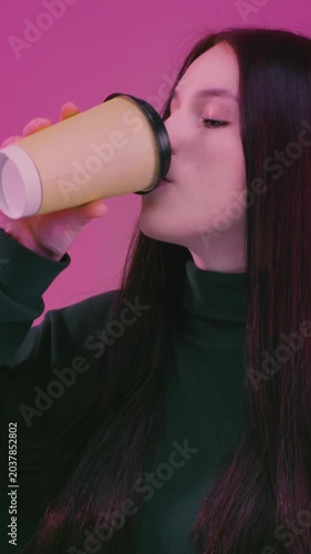 Teen brunette girl enjoying hot tea. Young woman holding take away coffee paper cup, cardboard. Female drink warm beverage, casual lifestyle moment, cozy mood. Student takes a sip from a paper cup