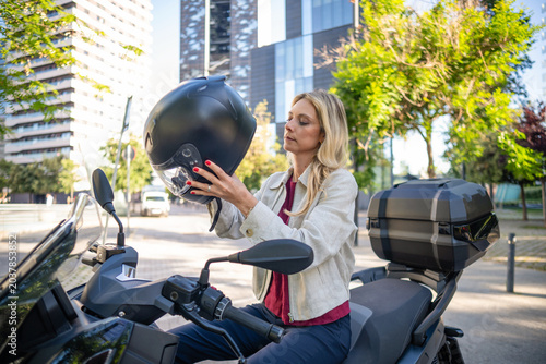 Woman preparing to ride scooter wearing helmet for urban commute