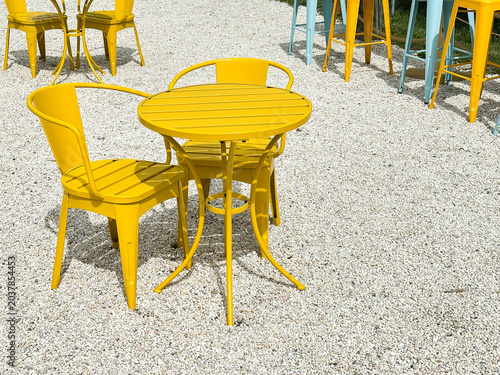 Yellow metal outdoor table chairs on gravel patio
