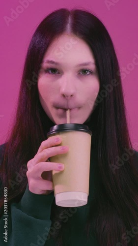 Teen brunette girl enjoying hot tea. Young woman holding take away coffee paper cup, cardboard. Female drink warm beverage outdoors, casual lifestyle moment, cozy mood, urban background, close-up shot