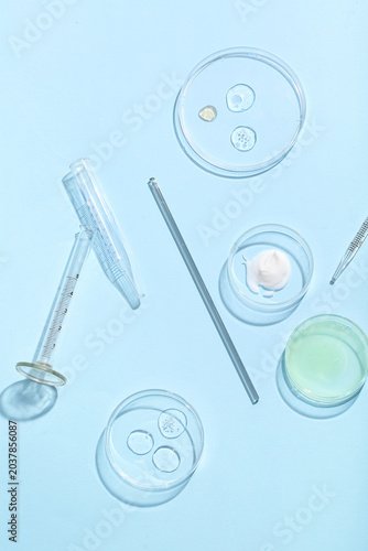 Petri dishes with different samples and professional glassware on blue backgr...