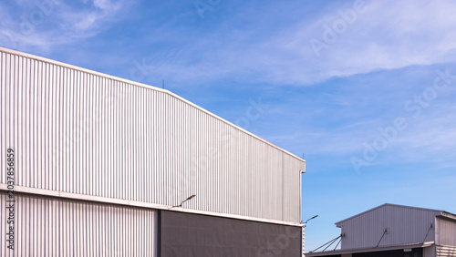 Cuadro en lienzo Industrial warehouse buildings with corrugated metal cladding against blue sky