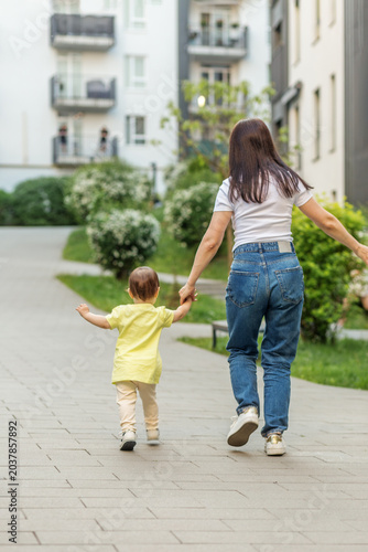 Mother Running With Toddler Daughter During Outdoor Family Walk