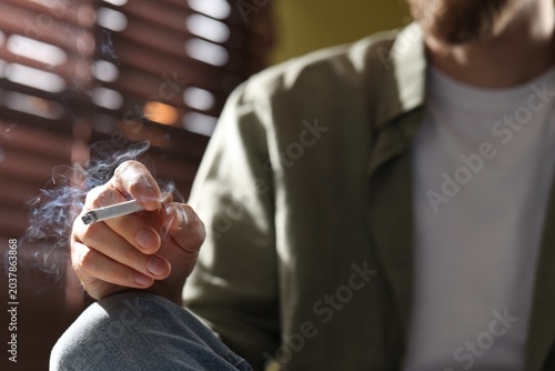 Photos Man smoking cigarette at home, closeup. Bad habit