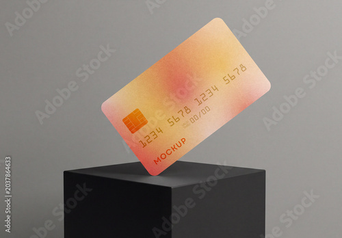 Floating credit card mockup with orange gradient design balancing on a black cube podium isolated on a gray background
