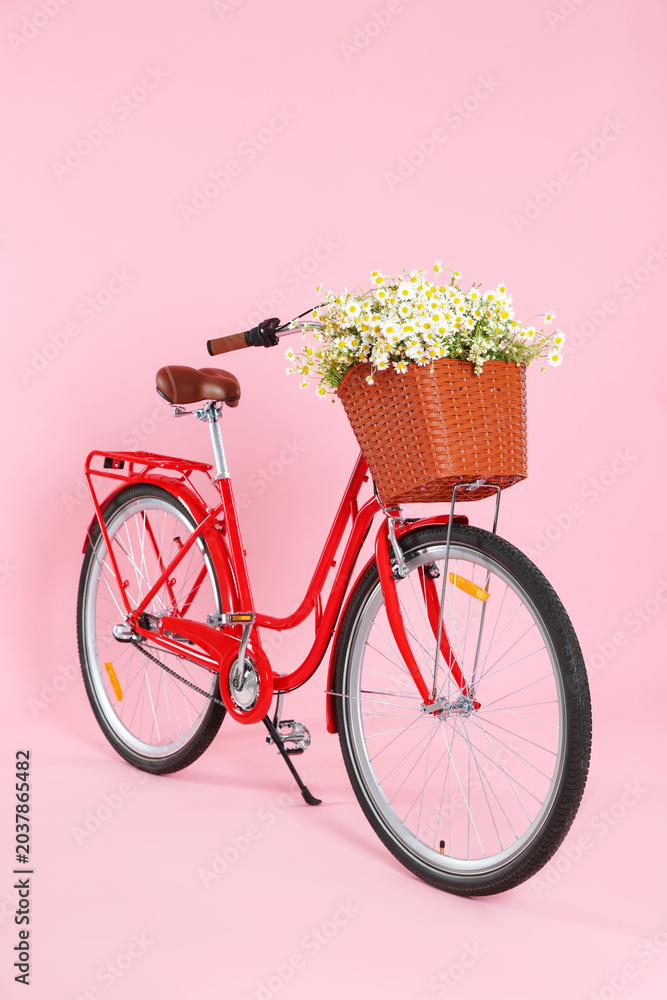Fototapeta premium Bicycle with basket of beautiful wildflowers on pink background