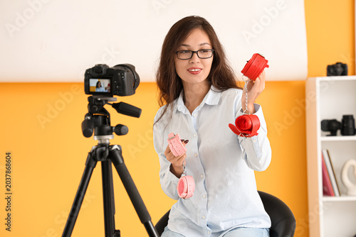 Female Asian blogger with handcuffs recording video in studio