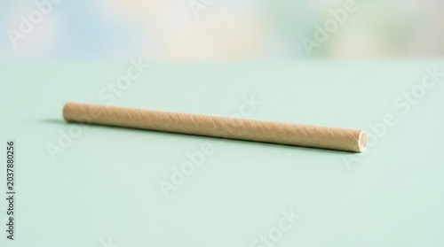 Simple eco-friendly paper straw lying on a pastel background, representing sustainable living.