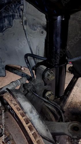  An impact wrench untightens a suspension bolt on a car.