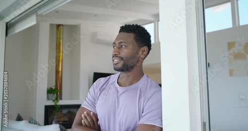 Mid-adult man standing in glass doorway, camera moving closer, shifting head and smiling to connect