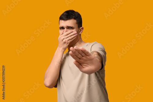 Tableau sur toile Handsome young man feeling bad smell on yellow background